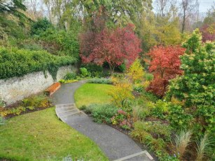 Sloping Garden. The path sweeps through the garden increasing its apparent width and allowing creation of a level area with a seat in a secluded sunny spot. 